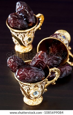 Still life with dates and golden Traditional Arabic coffee set with mini cup. Dark background. Vertical photo.