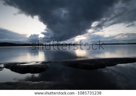 Rainclouds over a calm lake in sweden Royalty-Free Stock Photo #1085731238