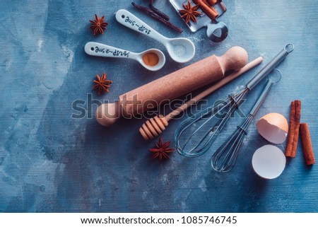 Whisks and measuring spoons on a blue concrete background. Cooking utensils flat lay with copy space. Baking tools and ingredients concept.