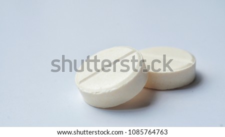 Close-up yellow tablet pill on white background. Selective focus.