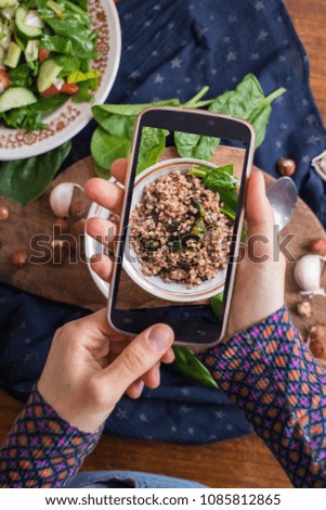 Woman hands take phone photo of food. Buckwheat porridge with fresh vegetables.  Russian traditional food.  Smartphone photography of lunch or dinner. Raw vegan vegetarian healthy food