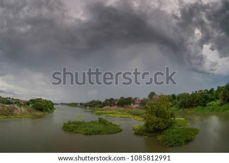 view of raining over Maeklong river with dark cloud moving over river and gren forest, Nakhon Chum, Ratchaburi, Thailand