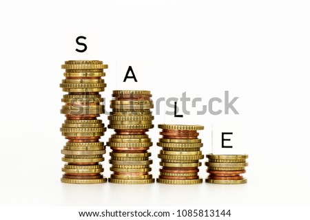 SALE word written with alphabet cubes with stack of coins