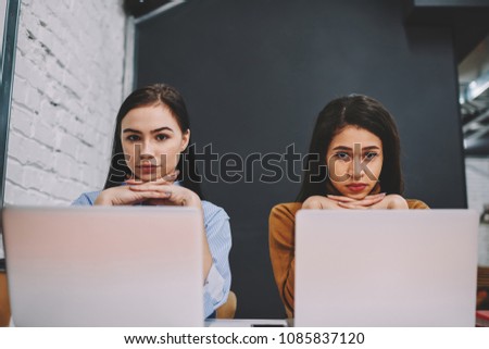 Portrait of female students sitting at laptop computers for learning in university concentrated on education,clever hipster girls looking at camera from netbooks spending time together on research 