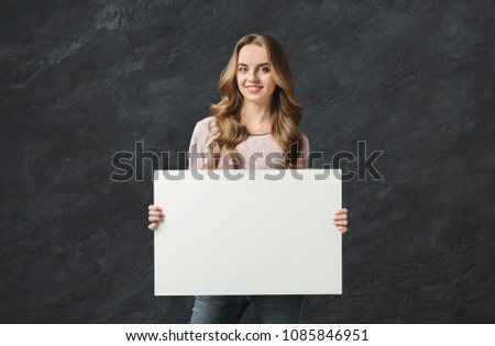 Young successful woman with blank white banner. Smiling girl holding advertising sheet, copy space