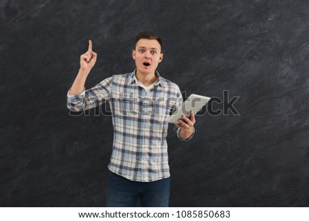 Handsome smiling man holding digital tablet and have an idea, black studio background, copy space