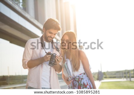 The young beautiful couple are looking at the photos they just made.