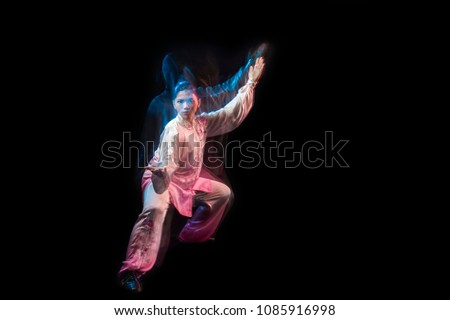 Girl in a white and pink wear engaged wushu against a dark background with slowspeed technic. Royalty-Free Stock Photo #1085916998