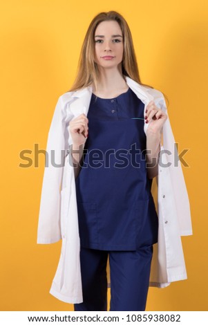European doctor in a surgical suit and white coat on a yellow background