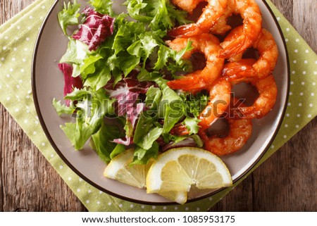 Honey soy king prawns and fresh salad close-up on a plate on a table. Horizontal top view from above
