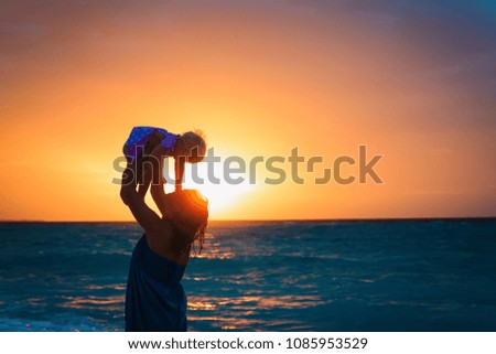 happy mother and baby daughter play at sunset