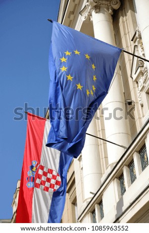 Flags of Croatia and European Union hang out together on wall of building, outside, wave on wind, blue sky