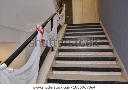 Steps of the stairs, railings decorated with a white cloth with scarlet ribbons for the entrance of the newlyweds to the wedding hall Royalty-Free Stock Photo #1085969864