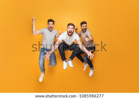 Three young excited men jumping together isolated over yellow background