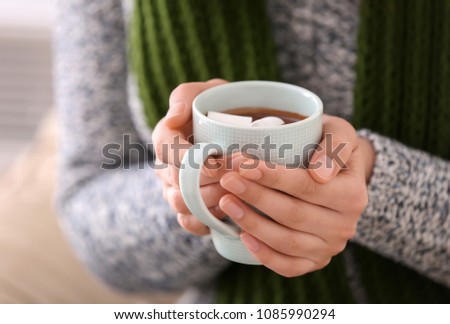 Woman holding cup of hot chocolate with marshmallow, closeup