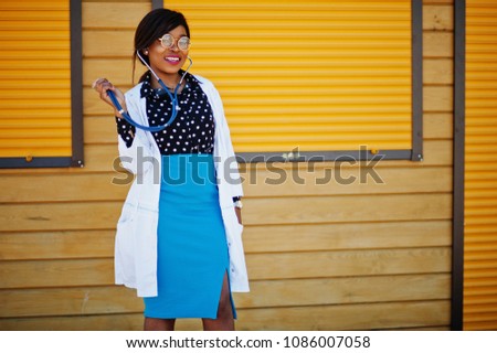 African american doctor female with stethoscope posed outdoor background yellow shutter.