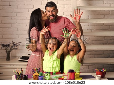 Girls drawing with colorful paints. Mother and father kissing with painted hands. Happy childhood and parenting. Family love and care concept. Arts and crafts.
