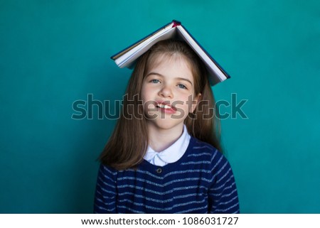 Tired school girl with a book on his head, education and school concept