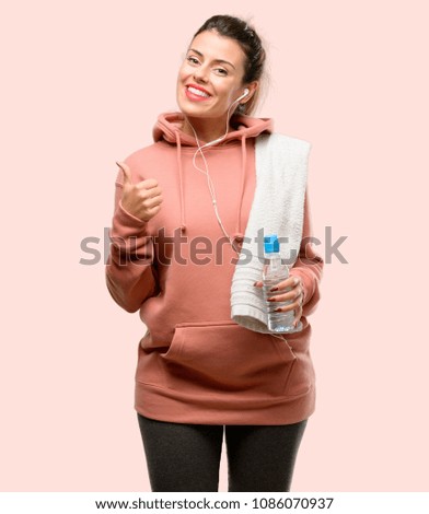 Young sport woman wearing workout sweatshirt smiling broadly showing thumbs up gesture to camera, expression of like and approval