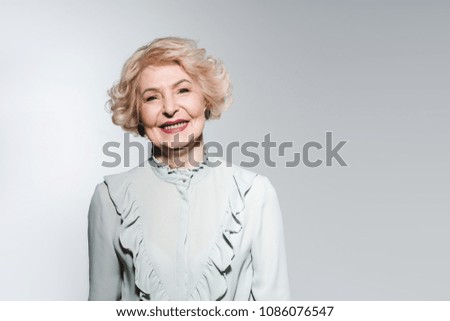 close-up portrait of happy senior woman in stylish shirt isolated on grey