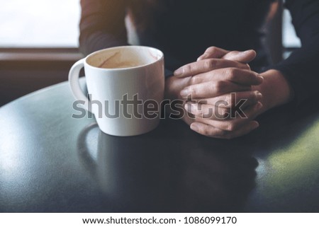 Closeup image of a woman holding hand and drinking hot coffee in cafe