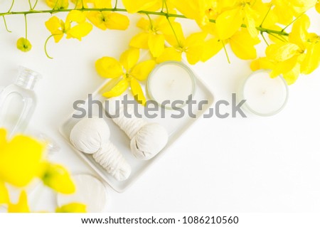 Bright spa background: candles and thai massage herbal bags with bottles and yellow flowers on white. Health, skin treatment concept. Text space Royalty-Free Stock Photo #1086210560