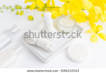 Bright spa background: candles and thai massage herbal bags with bottles and yellow flowers on white. Health, skin treatment concept Royalty-Free Stock Photo #1086210563