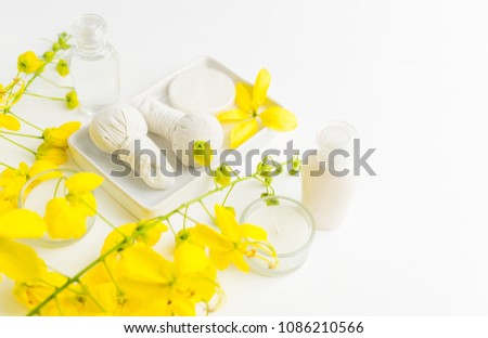 Bright spa background: candles and thai massage herbal bags with bottles and yellow flowers on white. Health, skin treatment concept Royalty-Free Stock Photo #1086210566