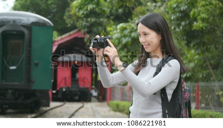 Woman travel and taking photo on digital camera at train station 