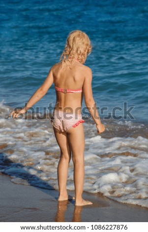 Blonde girl on the beach playing with sea waves