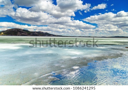 Picturesque landscape in Burabay National Nature Park, Kazakhstan. Shore of big Lake Borovoe (Burabay) in ice. Clouds are reflected in a frozen lake. May 2018.