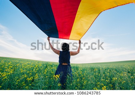 Woman holding the German flag outdoors on a meadow.  