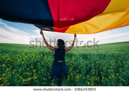 Woman holding the German flag outdoors on a meadow.  