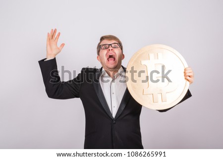 Portrait of a screaming businessman holds big golden bitcoin in his arms. Man in panic of cryptocurrency crash