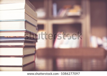 Books are placed on a wooden table and bookshelf in a library. education concept. with filter Tones retro vintage warm effect.