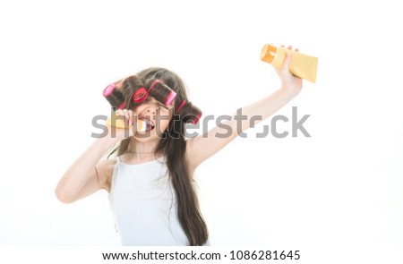 Little girl is holding a tube for the cream. Cute teen putting cream on her face. Little girl in hair curlers. Kid's fashion, cosmetics. Teen in hair curlers. Skincare, cosmetics, facial treatment.