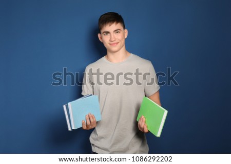 Teenage boy with books on color background