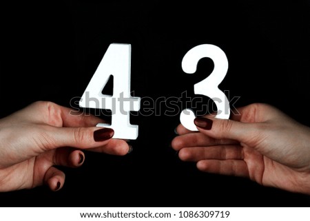 On a black background, female hand with number forty-three.