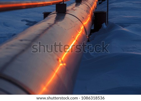 Gas pipelines, crane and pipes for gas and oil transportation, gas processing plant, against the backdrop of sunset