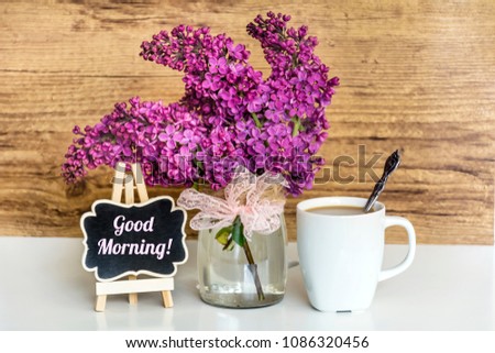 Bouquet of Lilac with Cup of Coffee and Good Morning Text on  Wooden Background .Spring Morning Concept