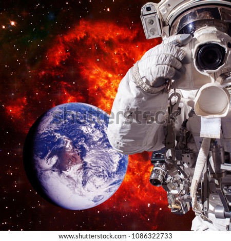 Astronaut with a camera makes a photo. Space and galaxies on the backdrop. The elements of this image furnished by NASA.