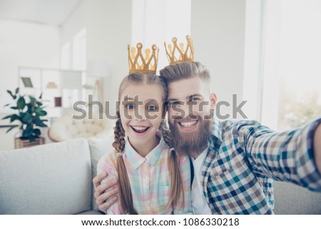 Self portrait of attractive cheerful joyful family with one parent shooting selfie on front camera, cute kid and stylish daddy wearing crowns on heads having video-call, with mother