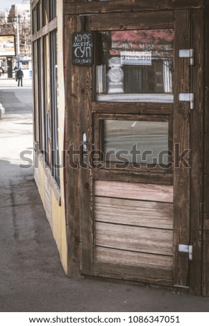 wooden door of small street cafe of Russian province city Saratov, with slate and signson it, at Russian language. Translation: "coffee, desserts, soup, sandwiches", "open". 