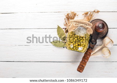 Pickled green peas in a jar. Stocks of food. Top view. On a wooden background. Copy space.