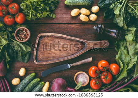 cutting board on a wooden background surrounded by vegetables, food frame, menu design, vegetables and spices on a wooden table