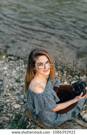 girl photographer sits during a photo shoot on the river bank