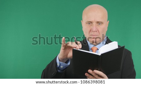 Serious Businessman Reading and Writing in Agenda