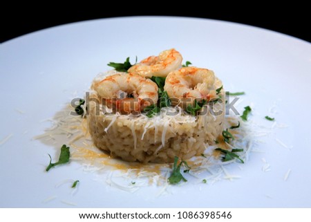Risotto with shrimps garnished with fresh parsley and parmesan cheese on a white plate. Paella. Italian food