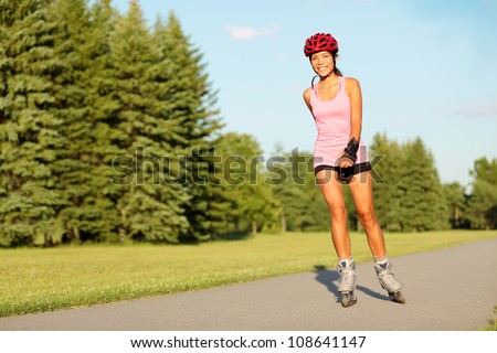 Roller skating girl in park rollerblading on inline skates. Mixed race Asian Chinese / Caucasian woman in outdoor activities.