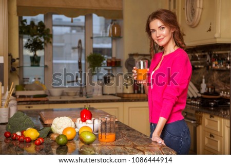 Beautiful young brunette woman in casual outfit cooking in the kitchen in her home. Luxury rich interior